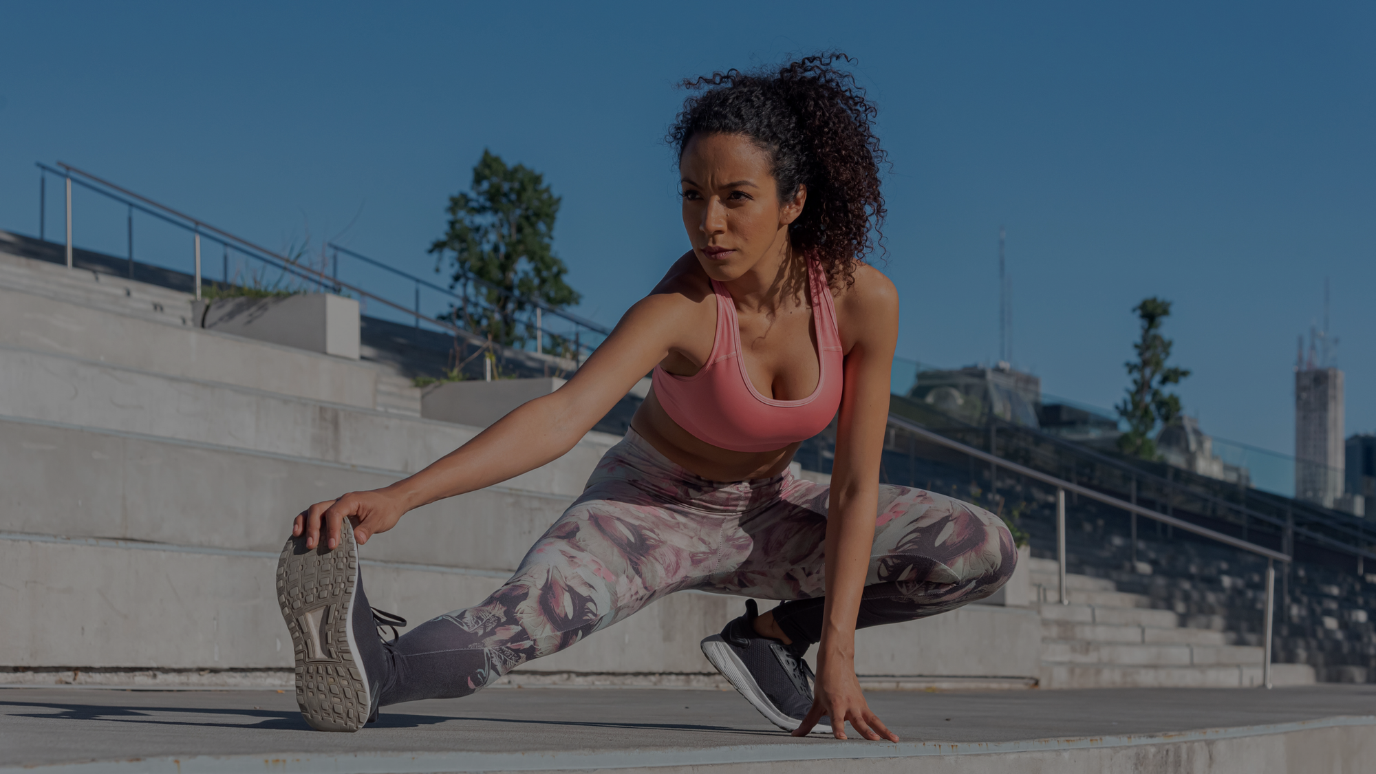 Woman stretching outdoors on a city street with buildings in the background
